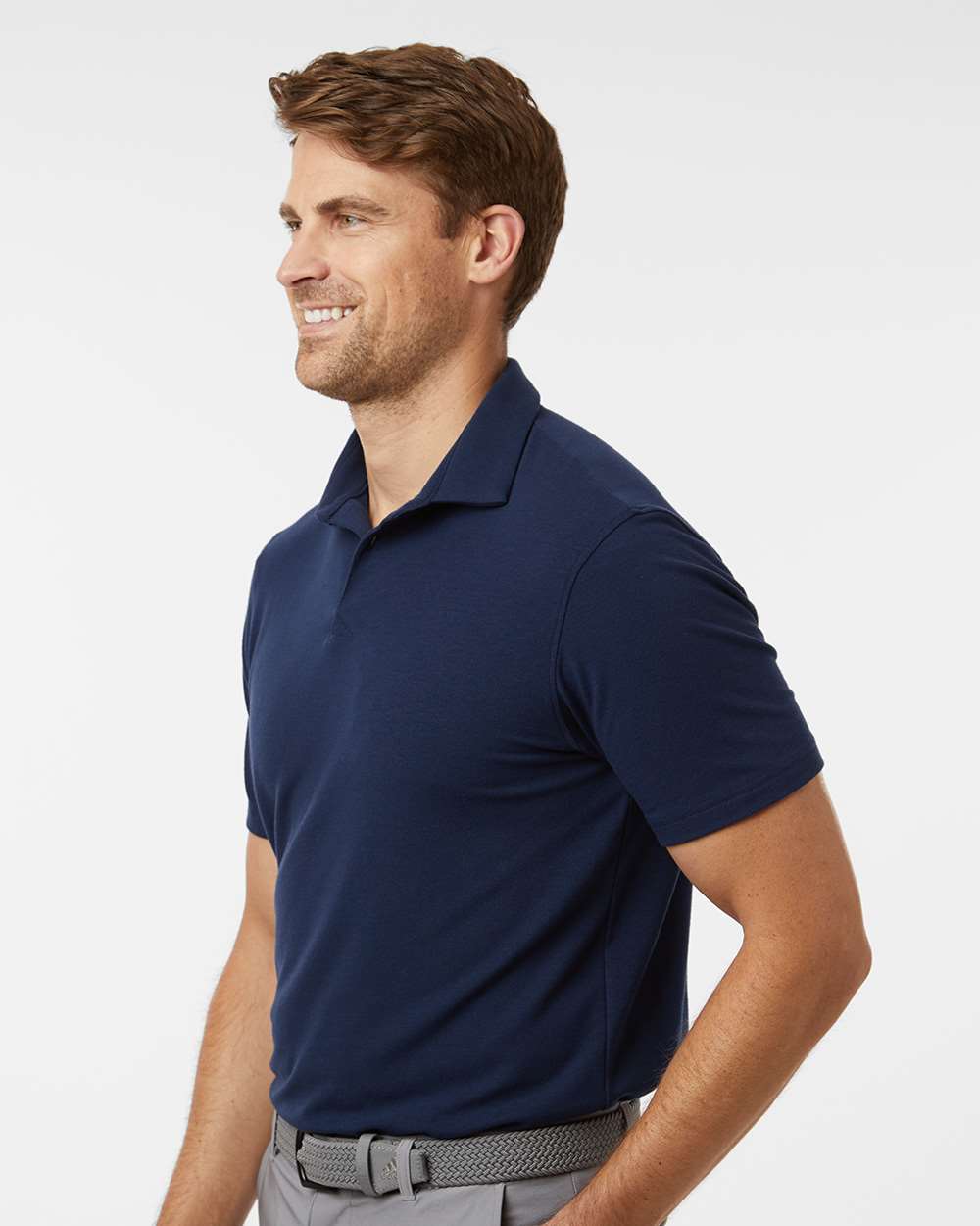 Man wearing a navy blue polo shirt on a light gray background. Adidas Men's Blended Polo, Embroidered by Helmsman Stitch Co.