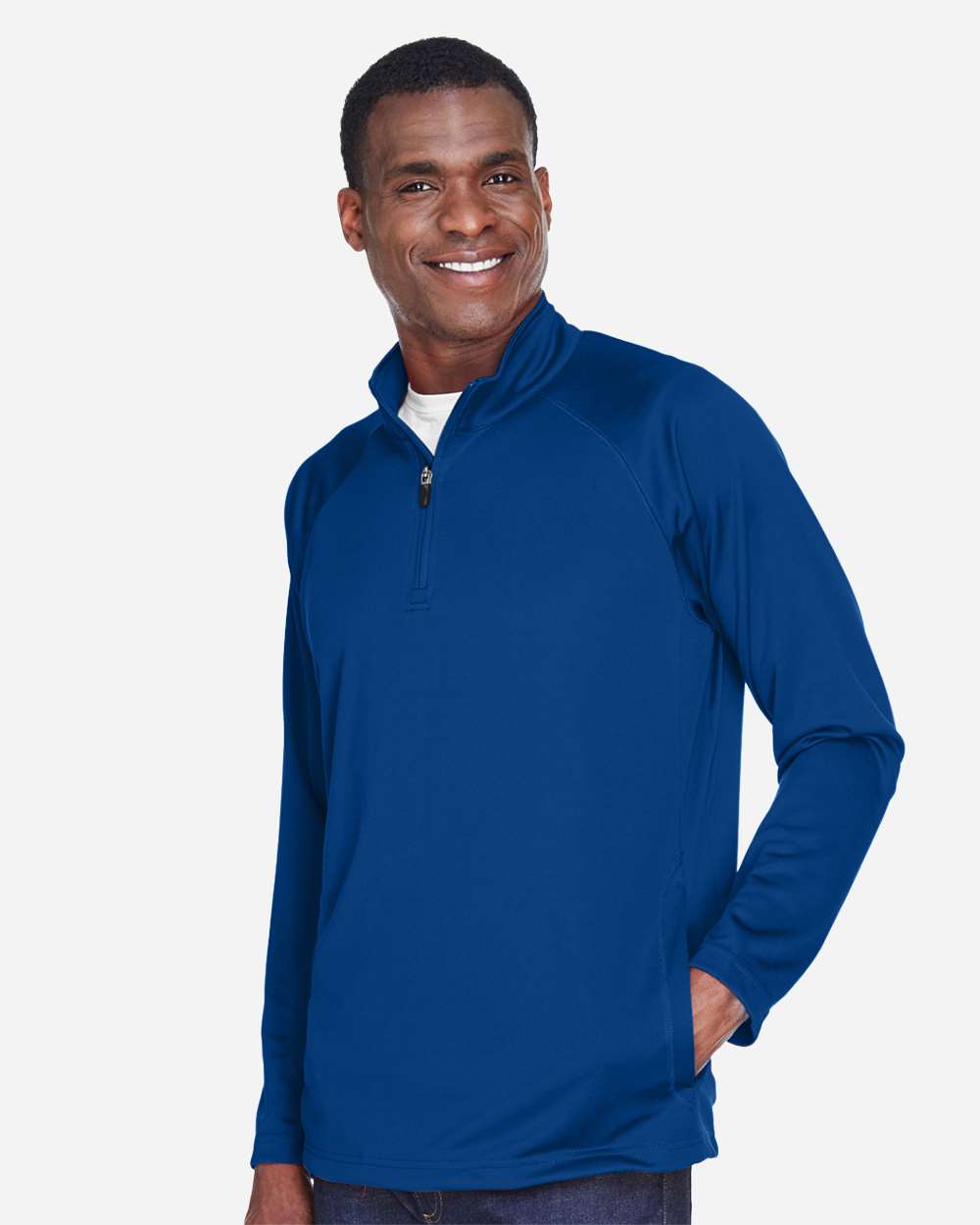 Man wearing a blue long-sleeve shirt with a quarter zip on a white background. Devon & Jones Men's Stretch Tech-Shell® Compass Quarter-Zip Pullover, Embroidered by Helmsman Stitch Co.