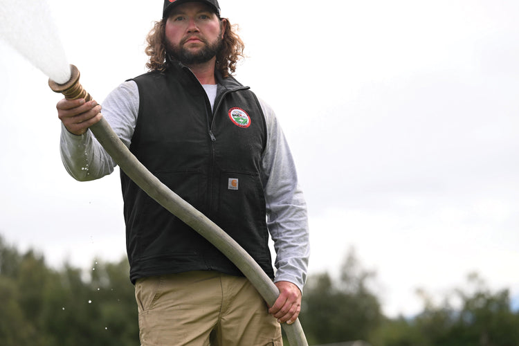 man watering grass wearing an embroidered vest