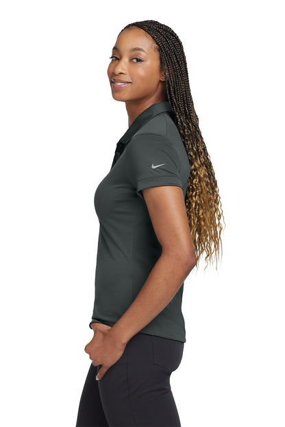 Woman wearing a dark gray Nike polo shirt on a white background, embroidered Nike Women's Dri-FIT Players Modern Fit Polo