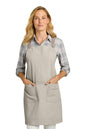 Woman wearing a beige apron on a white background. Port Authority® Signature Heavy Twill Crossback Apron, Embroidered