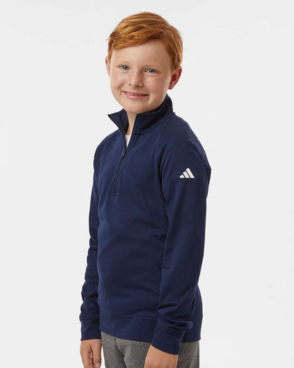 Child wearing a navy Adidas pullover on a white background. Adidas Youth Performance Quarter-Zip Pullover, Embroidered by Helmsman Stitch Co.