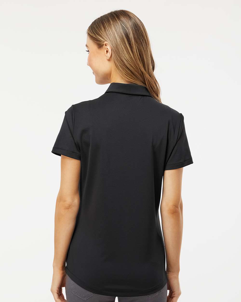 Woman wearing a black polo shirt on a white background. Adidas Women's Ultimate365 Solid Polo, Embroidered by Helmsman Stitch Co.