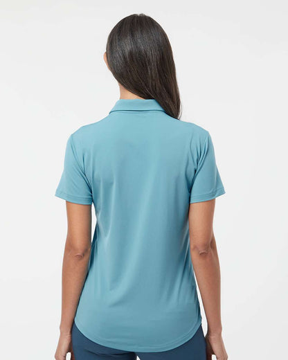 Person wearing a blue polo shirt on a white background. Adidas Women's Ultimate365 Solid Polo, Embroidered by Helmsman Stitch Co.