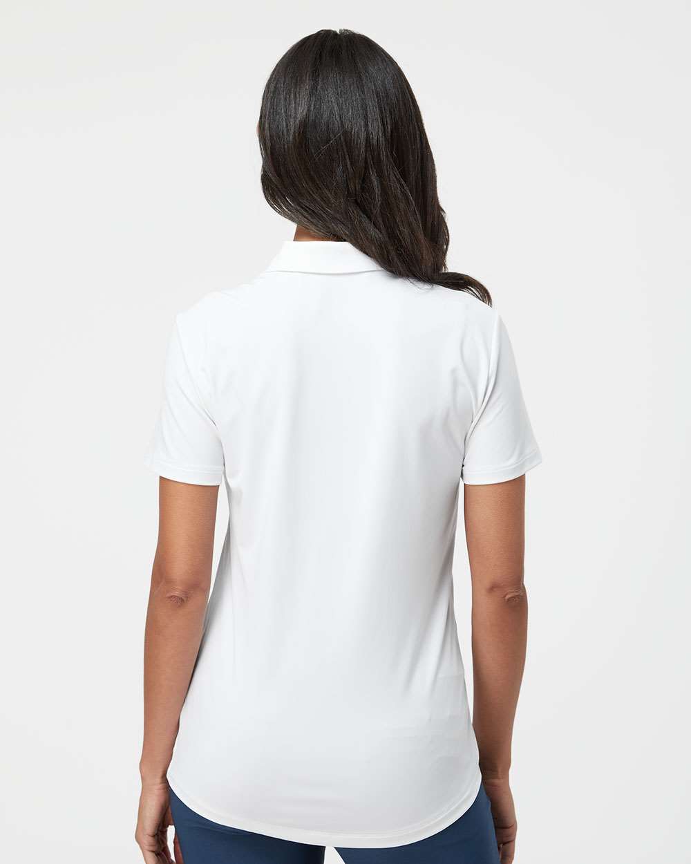 Person wearing a white polo shirt on a plain background. Adidas Women's Ultimate365 Solid Polo, Embroidered by Helmsman Stitch Co.