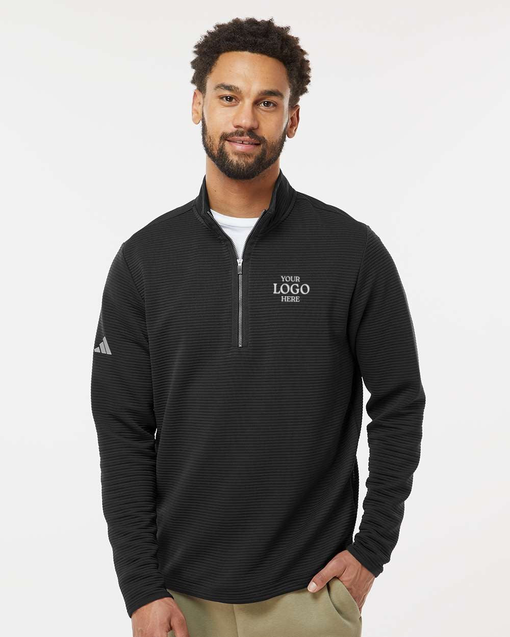 Man wearing a black Adidas quarter-zip pullover with a logo on a white background. Adidas Men's Spacer Quarter-Zip Pullover, Embroidered