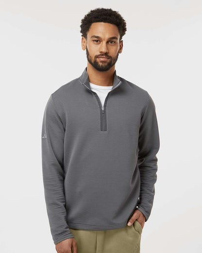 Man wearing a gray striped pullover with a white background. Adidas Men's Spacer Quarter-Zip Pullover, Embroidered by Helmsman Stitch Company