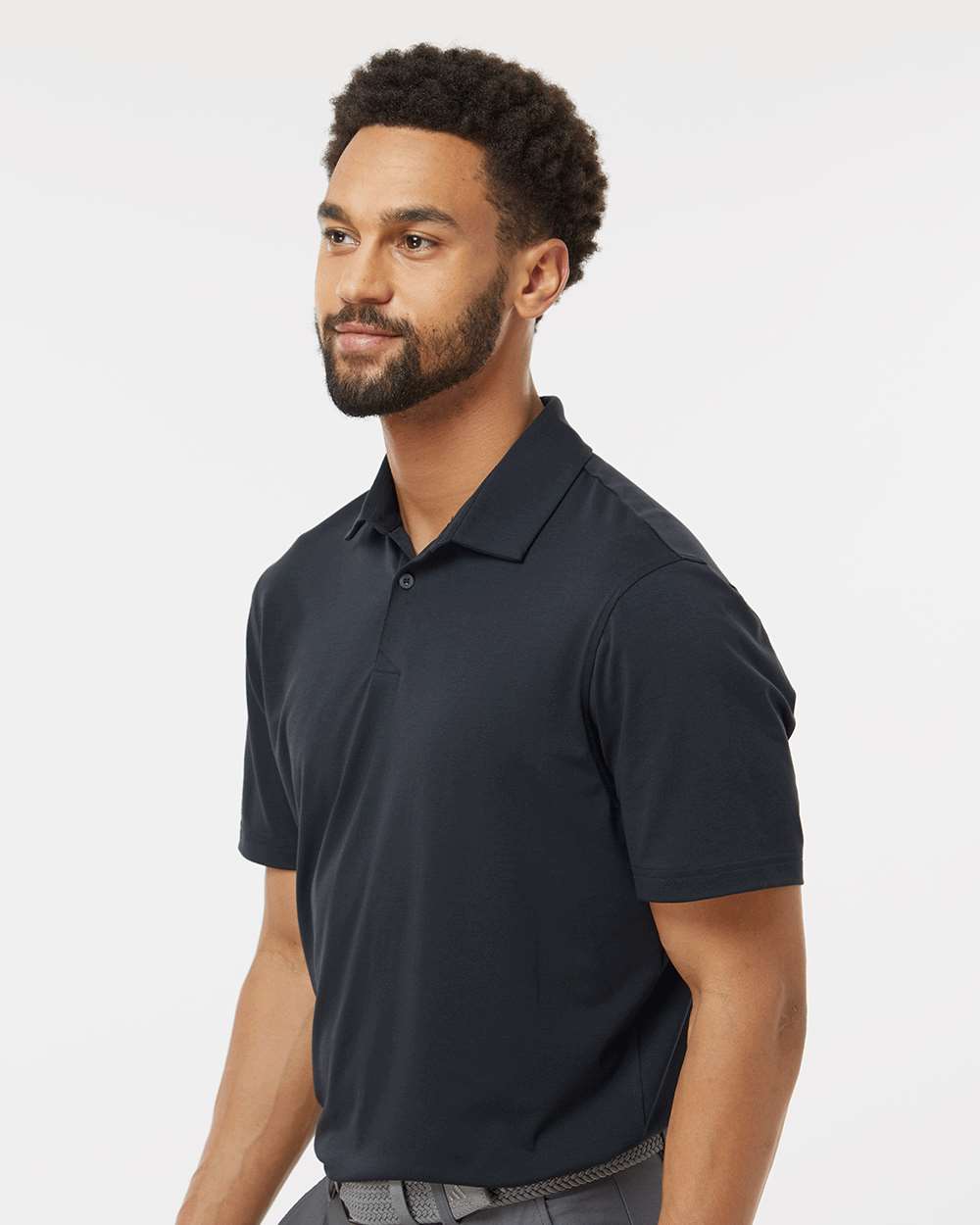 Man wearing a black polo shirt against a white background. Adidas Men's Blended Polo, Embroidered by Helmsman Stitch Co.