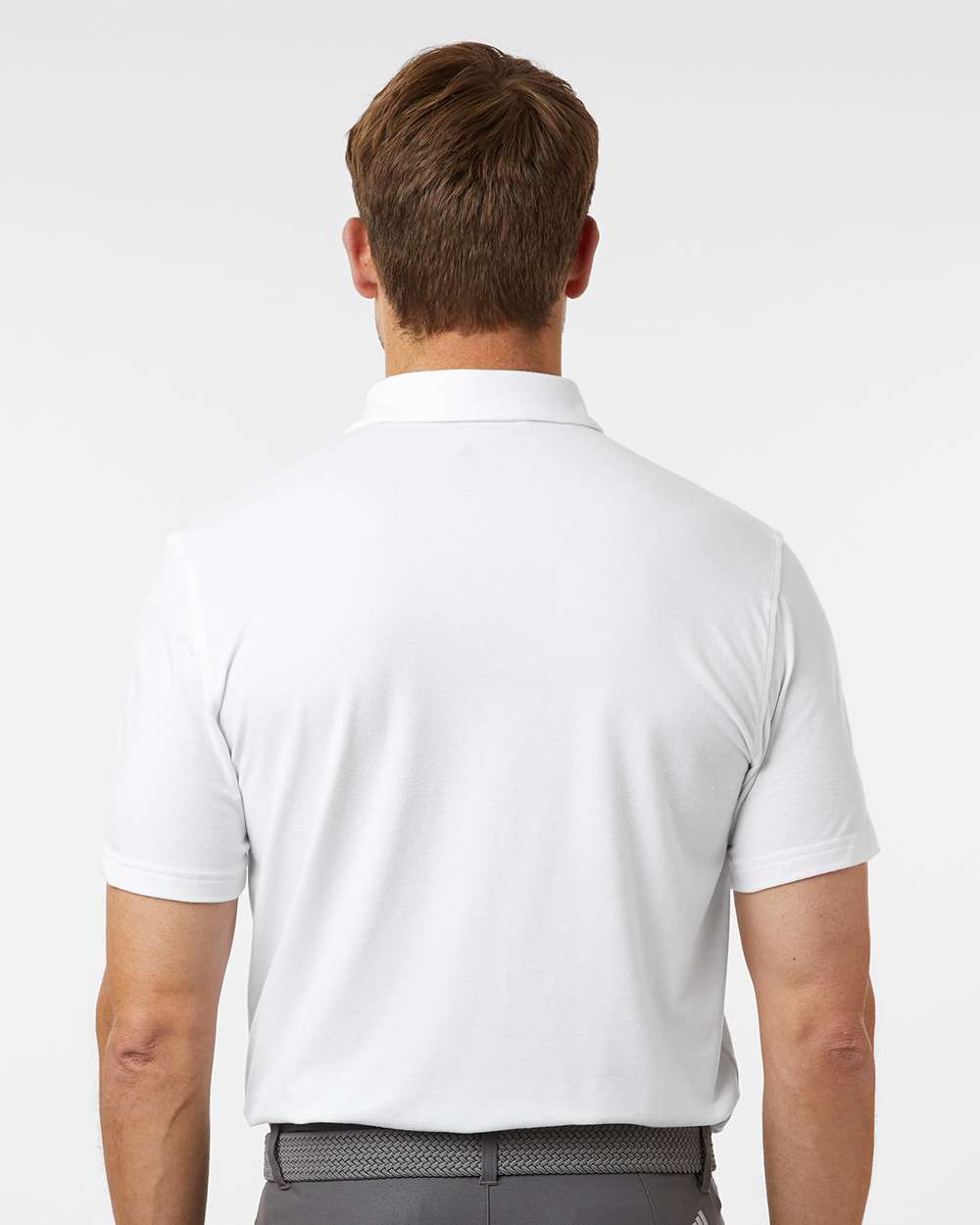 Man wearing a white polo shirt on a plain background. Adidas Men's Blended Polo, Embroidered by Helmsman Stitch Co.