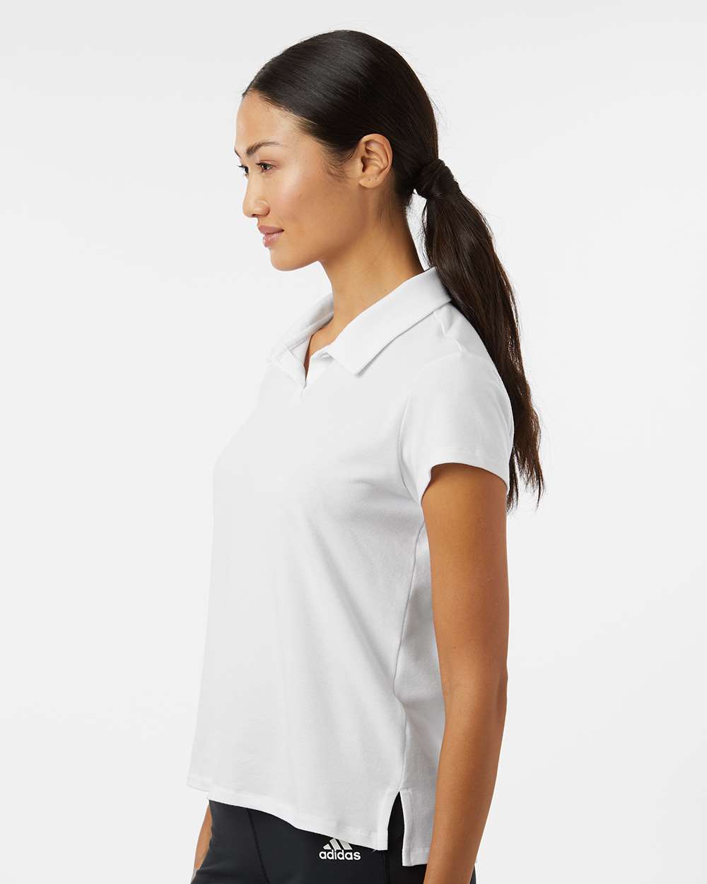 Woman wearing a white Adidas polo shirt on a white background. Adidas Women's Blended Polo, Embroidered by helmsman Stitch Co.