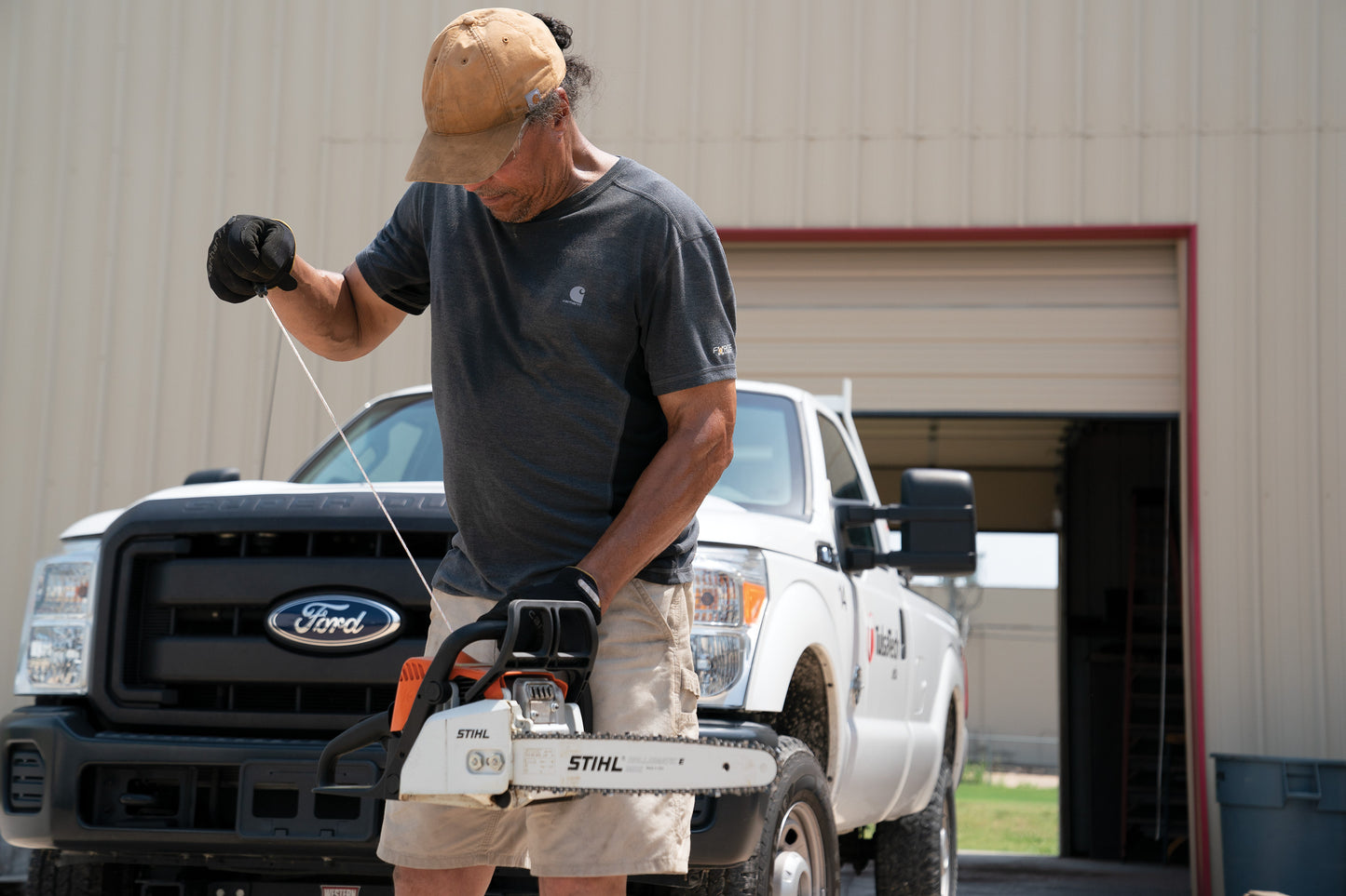 Man using a chainsaw in front of a Ford truck Carhartt® Cotton Canvas Cap, Embroidered