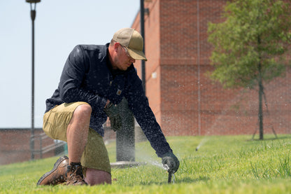 Person using a sprinkler to water grass in front of a brick building, Carhartt® Rugged Professional™ Series Cap, Embroidered