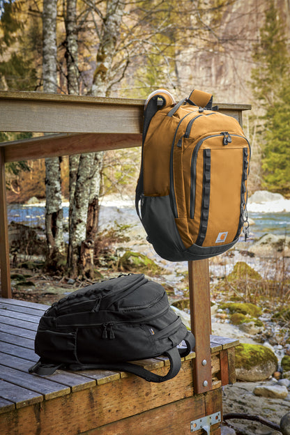 Two backpacks, one yellow and one black, on a wooden bench with a scenic background of trees and water.