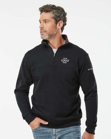 Man wearing a black pullover with a logo on a light gray background. Columbia Men's Hart Mountain™ II Half-Zip Pullover, Embroidered