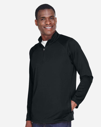 Man wearing a black long-sleeve shirt with a quarter-zip on a white background. Devon & Jones Men's Stretch Tech-Shell® Compass Quarter-Zip Pullover, Embroidered by Helmsman Stitch Co.
