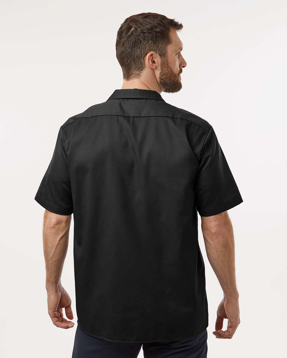 Man wearing a black short-sleeve shirt on a white background. Dickie's Men's Shirt Sleeve Work Shirt, Embroidered by Helmsman Stitch Co.