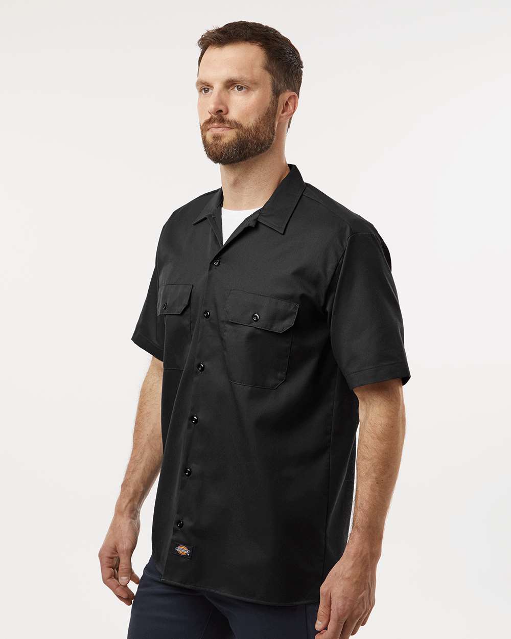 Man wearing a black short-sleeve shirt on a white background. Dickie's Men's Shirt Sleeve Work Shirt, Embroidered by Helmsman Stitch Co.