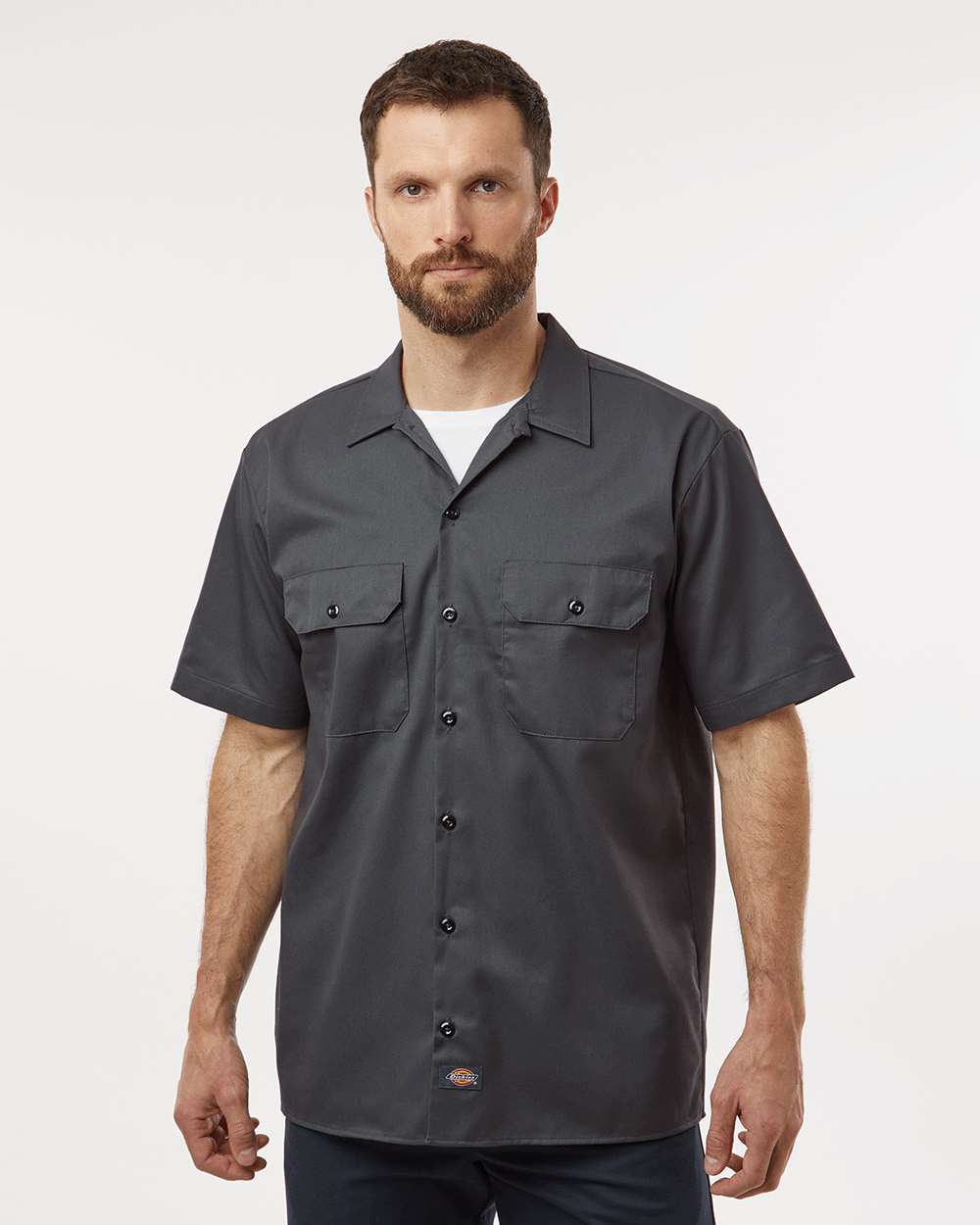 Man wearing a dark gray short-sleeve shirt on a white background. Dickie's Men's Shirt Sleeve Work Shirt, Embroidered by Helmsman Stitch Co.