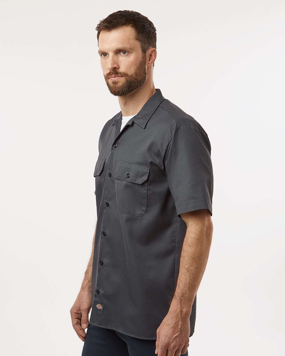 Man wearing a dark gray short-sleeve shirt on a white background. Dickie's Men's Shirt Sleeve Work Shirt, Embroidered by Helmsman Stitch Co.
