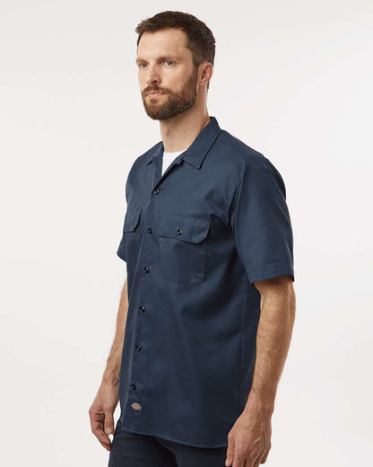Man wearing a navy blue short-sleeve shirt on a white background. Dickie's Men's Shirt Sleeve Work Shirt, Embroidered by Helmsman Stitch Co.