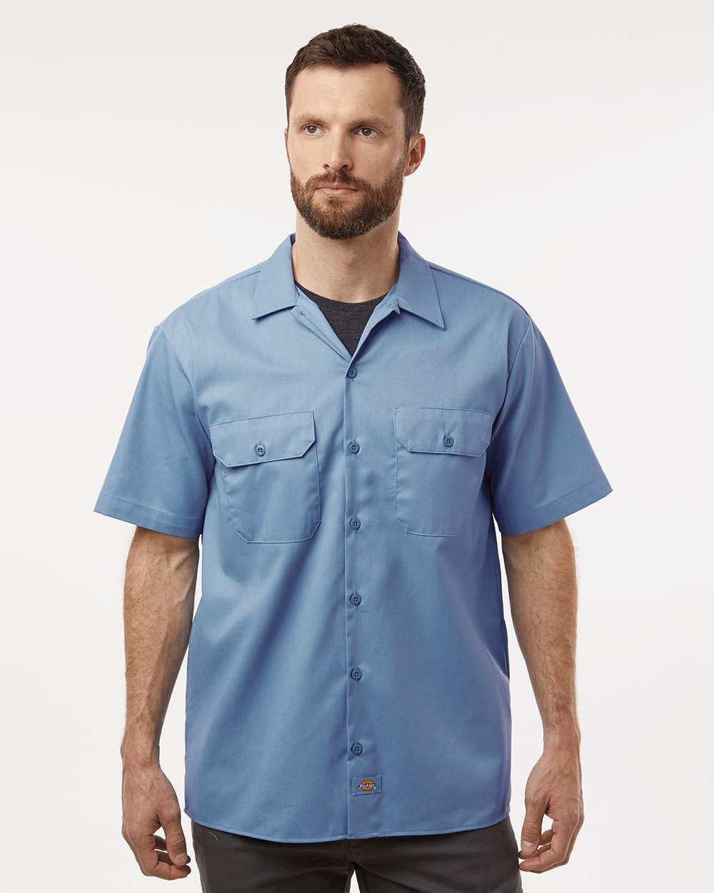 Man wearing a blue short-sleeve shirt on a white background. Dickie's Men's Shirt Sleeve Work Shirt, Embroidered by Helmsman Stitch Co.