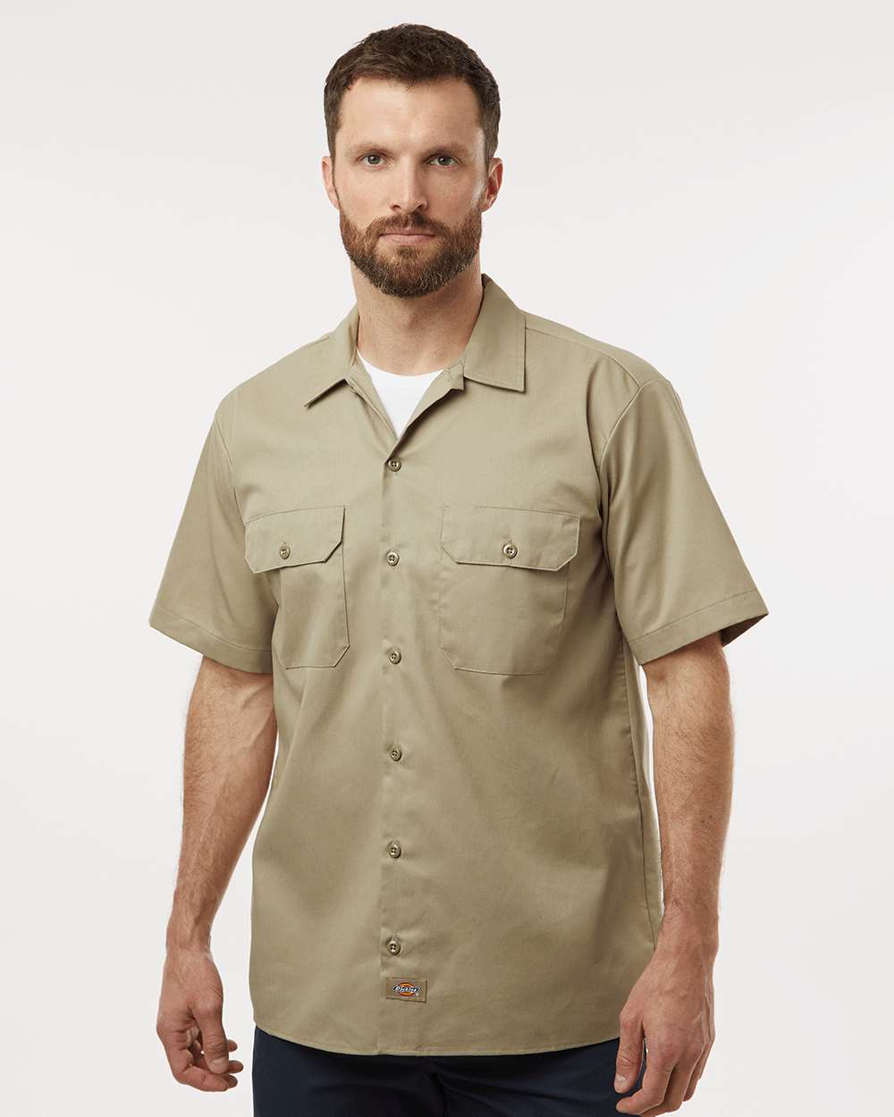 Man wearing a beige short-sleeve shirt on a white background. Dickie's Men's Shirt Sleeve Work Shirt, Embroidered by Helmsman Stitch Co.