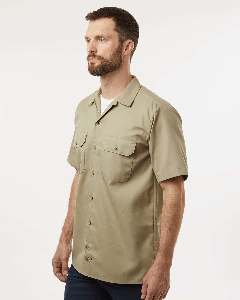 Man wearing a beige short-sleeve shirt on a white background. Dickie's Men's Shirt Sleeve Work Shirt, Embroidered by Helmsman Stitch Co.