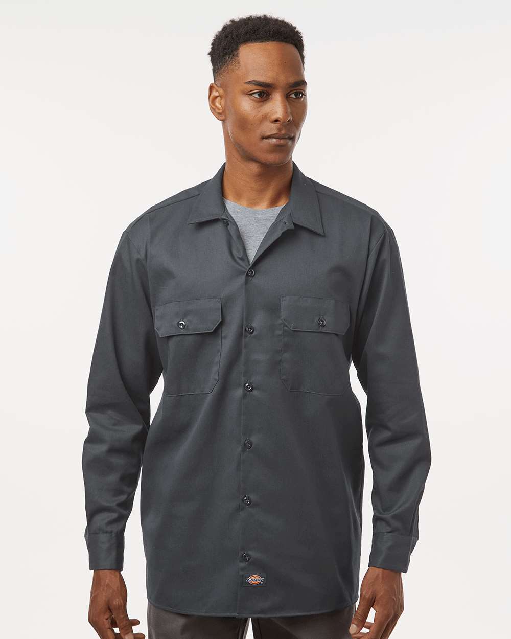Man wearing a dark gray button-up shirt on a white background. Dickie's Men's Long Sleeve Work Shirt, Embroidered by Helmsman Stitch Co.