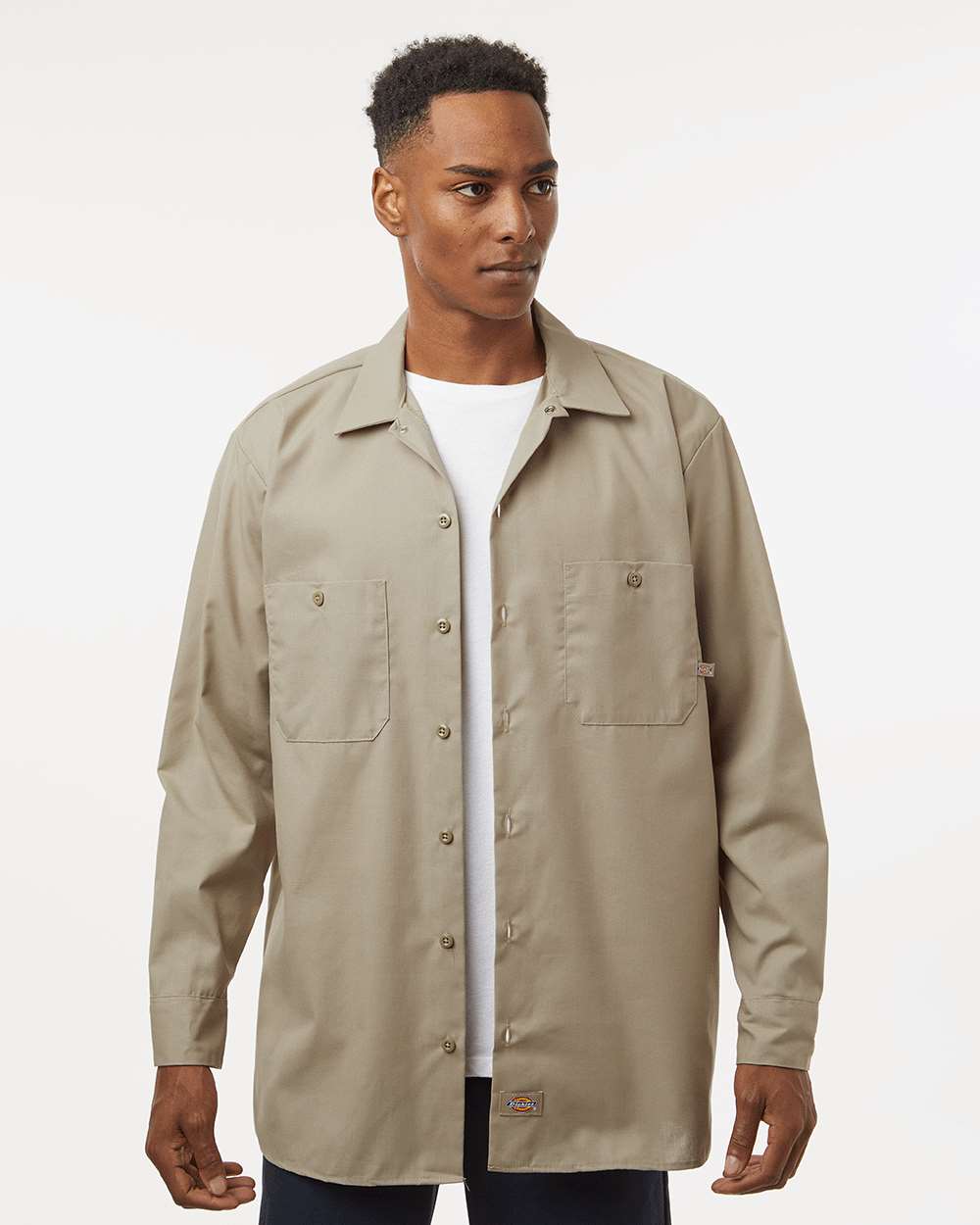 Man wearing a beige button-up shirt over a white t-shirt on a plain background. Dickie's Men's Industrial long Sleeve Work Shirt, Embroidered by Helmsman Stitch Co.
