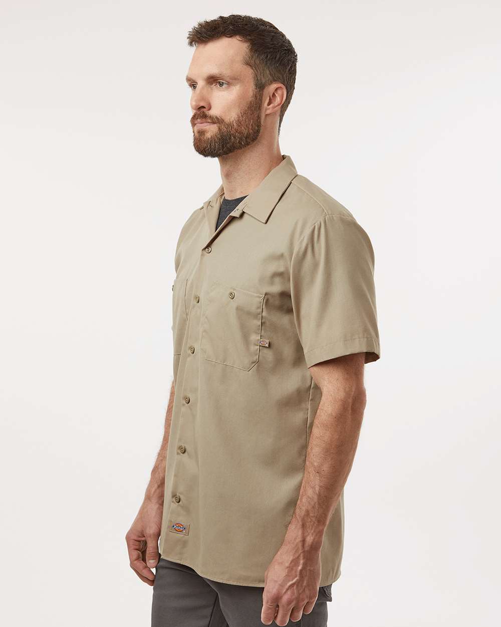 Man wearing a beige short-sleeve shirt on a white background. Dickie's Men's Industrial Short Sleeve Work Shirt, Embroidered by Helmsman Stitch Co.