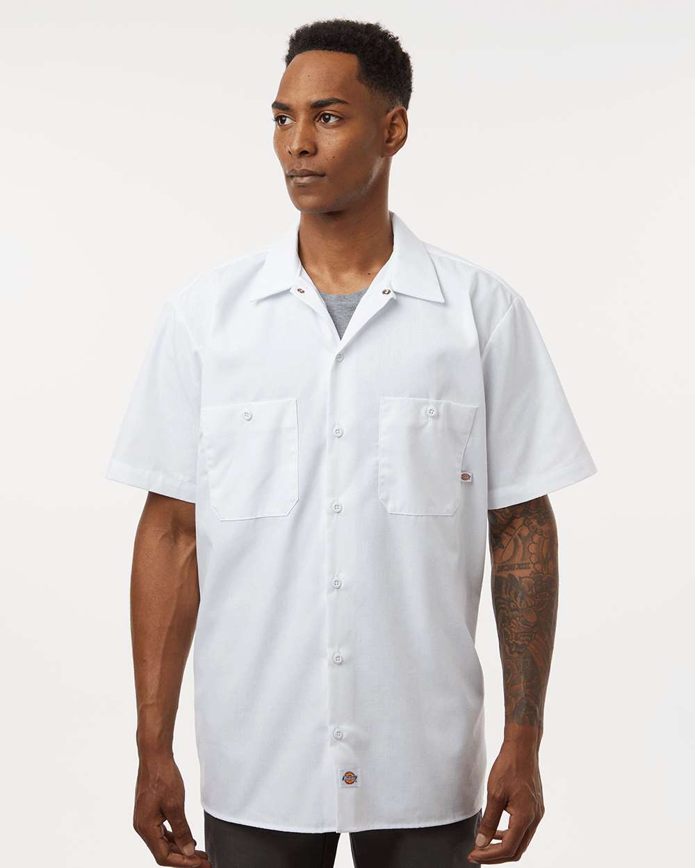 Man wearing a white short-sleeve button-up shirt on a plain background. Dickie's Men's Industrial Short Sleeve Work Shirt, Embroidered by Helmsman Stitch Co.
