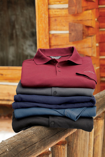 Stack of folded polo shirts in red, blue, and black on a wooden surface with a rustic background. Eddie Bauer® Performance Polo, Embroidered