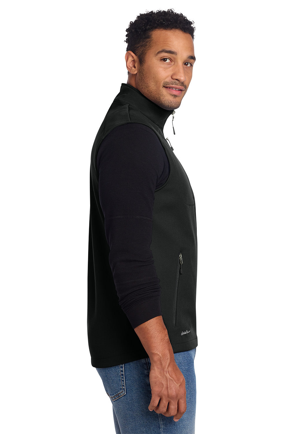 Man wearing a black vest over a black shirt with blue jeans on a white background, embroidered Eddie Bauer® Stretch Soft Shell Vest