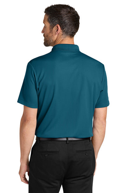 Man wearing a teal polo shirt and black pants on a white background. Port Authority® Plaited Pique Polo, Embroidered by Helmsman Stitch Co.