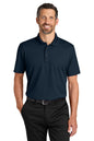 Man wearing a navy polo shirt and black pants on a white background. Port Authority® Plaited Pique Polo, Embroidered by Helmsman Stitch Co.