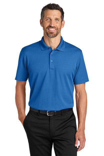 Man wearing a blue polo shirt and black pants on a white background. Port Authority® Plaited Pique Polo, Embroidered by Helmsman Stitch Co.