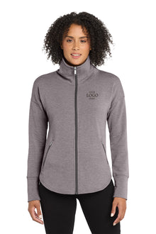 Woman wearing a gray full-zip jacket with a logo on a white background, embroidered OGIO® Women's Luuma Full-Zip Fleece
