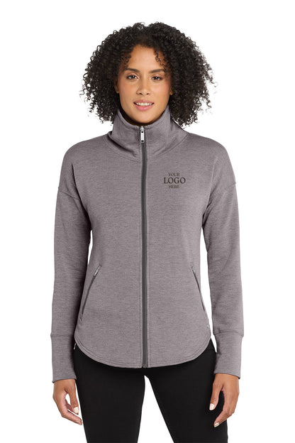 Woman wearing a gray full-zip jacket with a logo on a white background, embroidered OGIO® Women's Luuma Full-Zip Fleece