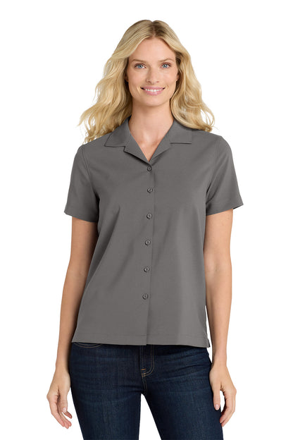 Woman wearing a gray short-sleeve blouse with a collar on a white background embroidered Port Authority® Women's Short Sleeve Performance Staff Shirt