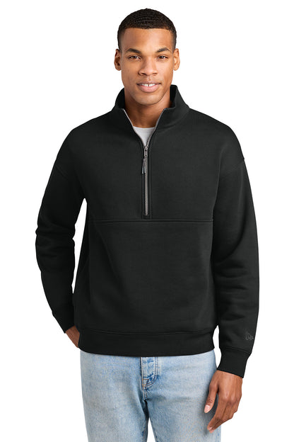 A man wearing a black quarter-zip pullover sweatshirt with a mock neck and a horizontal seam across the chest, paired with light blue jeans, against a plain white background. New Era® Heritage Fleece 1/2-Zip, Embroidered