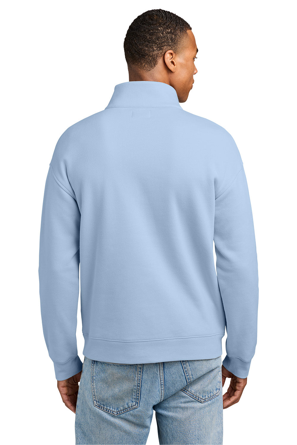 A man viewed from the back wearing a light blue quarter-zip pullover sweatshirt and light-wash blue jeans against a plain white background. New Era® Heritage Fleece 1/2-Zip, Embroidered