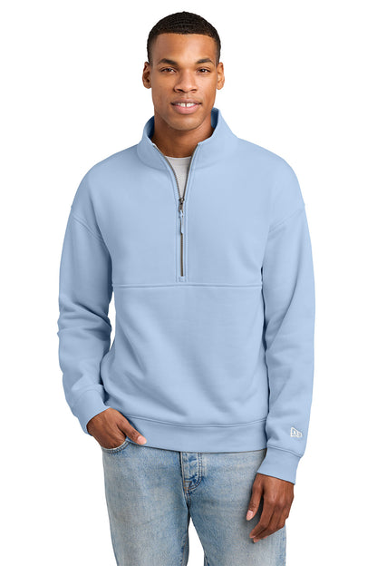 A man wearing a light blue quarter-zip sweatshirt and light-wash jeans, standing against a plain white background. New Era® Heritage Fleece 1/2-Zip, Embroidered