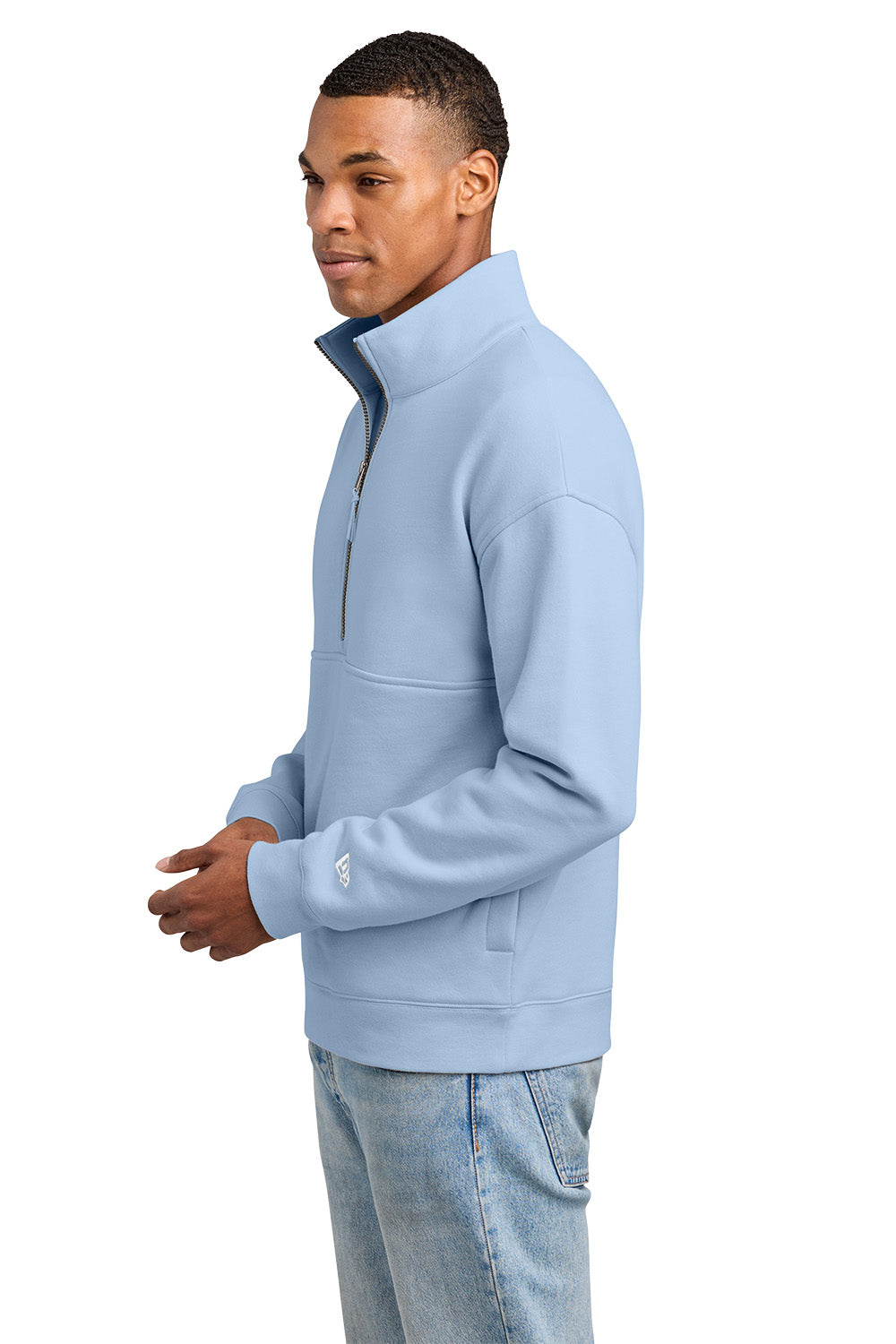 A man wearing a light blue quarter-zip sweatshirt and light-wash jeans, shown in profile against a plain white background. New Era® Heritage Fleece 1/2-Zip, Embroidered