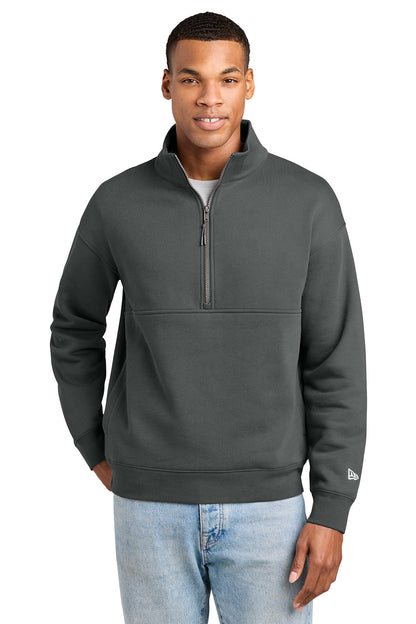 A man wearing a dark gray quarter-zip pullover sweatshirt with a small white New Era logo on the left sleeve, paired with light blue jeans, against a plain white background. New Era® Heritage Fleece 1/2-Zip, Embroidered