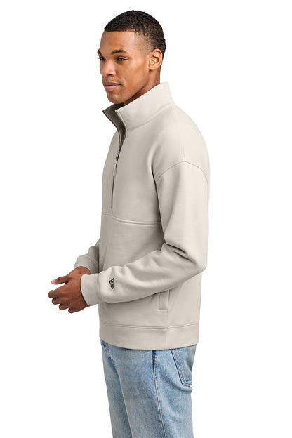 A man wearing a light beige quarter-zip pullover sweatshirt and light blue jeans, shown from a side profile against a plain white background. New Era® Heritage Fleece 1/2-Zip, Embroidered