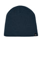 A dark navy blue ribbed knit beanie hat with a small black and white The North Face logo patch on the lower right side, shown against a plain white background. The North Face® Mountain Beanie, Embroidered