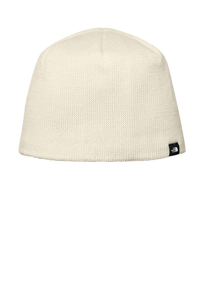 An off-white knit beanie hat with a small black and white The North Face logo patch on the lower right side, shown against a plain white background. The North Face® Mountain Beanie, Embroidered