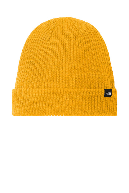 A bright yellow ribbed knit beanie hat with a folded cuff and a small black The North Face logo patch on the side, shown against a plain white background. The North Face® Circular Rib Beanie, Embroidered