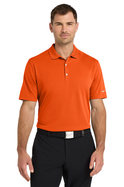 Man wearing an orange Nike polo shirt and black pants on a white background. Nike Dri-FIT Micro Pique 2.0 Polo, Embroidered by Helmsman Stitch Co.