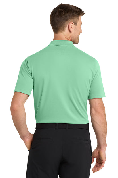 Man wearing a green polo shirt and black pants on a white background. Nike Dri-FIT Micro Pique 2.0 Polo, Embroidered by Helmsman Stitch Co.